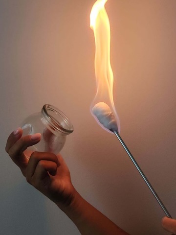 A glass cup being warmed with a flame for fire cupping at Excelsior & Grand Chiropractic