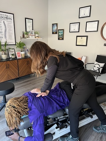 Dr. Heather adjusting a patient’s mid-back on a chiropractic table in St. Louis Park, MN